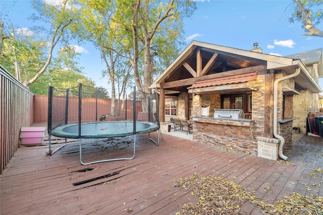 deck featuring a trampoline and exterior kitchen