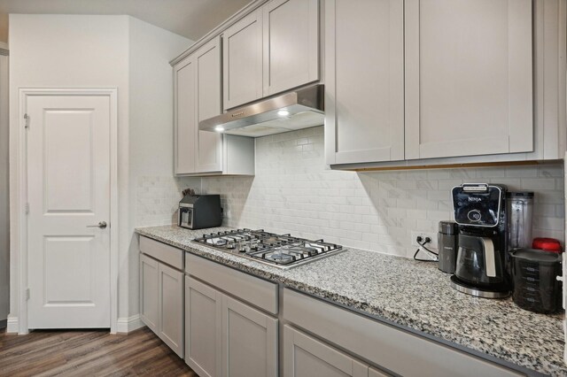 kitchen featuring dark hardwood / wood-style floors, decorative backsplash, light stone countertops, and stainless steel gas cooktop