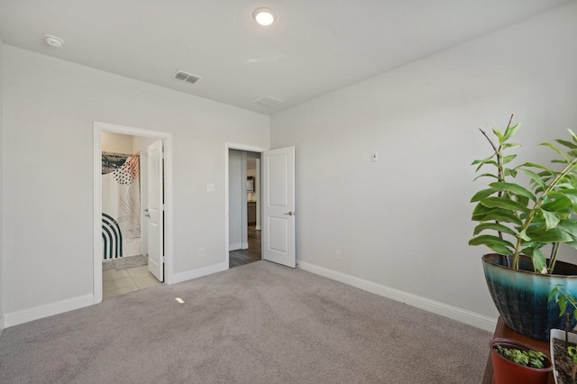 unfurnished bedroom featuring a walk in closet and light colored carpet