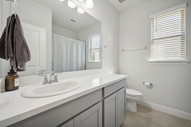 bathroom featuring toilet, vanity, tile patterned floors, and a wealth of natural light