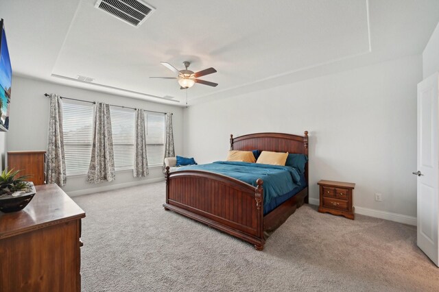 bedroom with light carpet, a raised ceiling, and ceiling fan