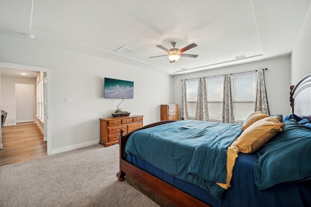 carpeted bedroom with ceiling fan and a tray ceiling