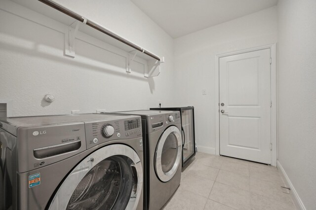 laundry area with separate washer and dryer and light tile patterned flooring