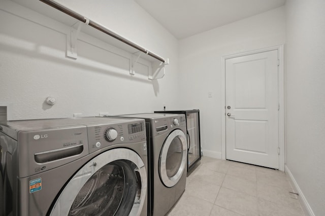 clothes washing area with light tile patterned floors and washing machine and clothes dryer