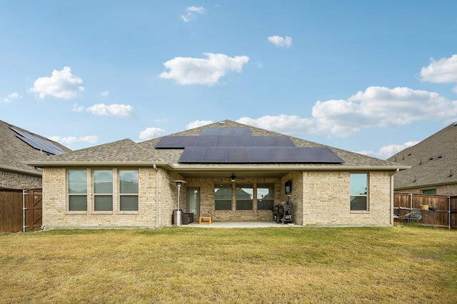 back of house with solar panels, ceiling fan, a patio area, and a lawn