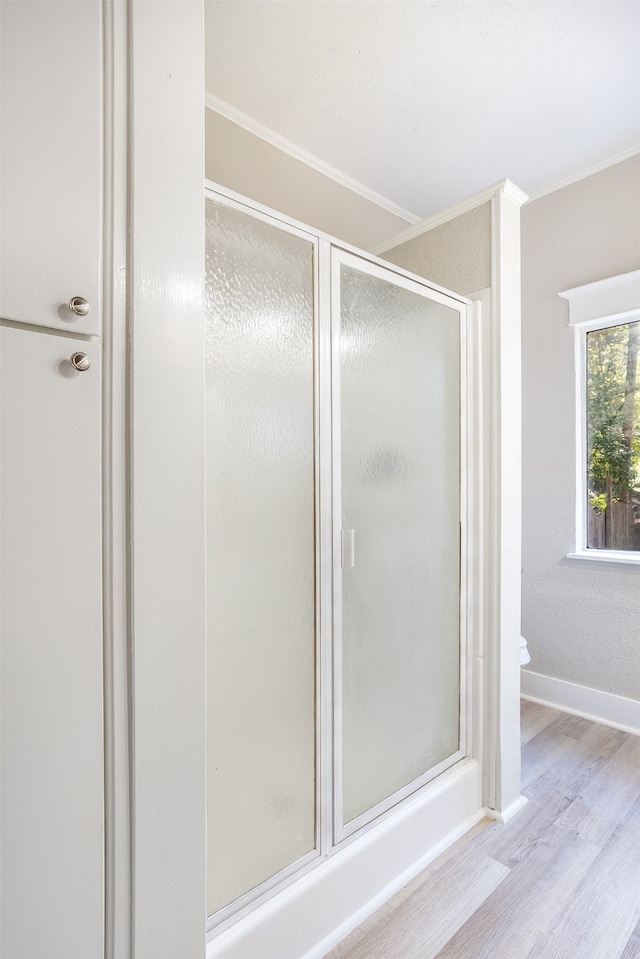 bathroom featuring hardwood / wood-style floors, ornamental molding, and walk in shower