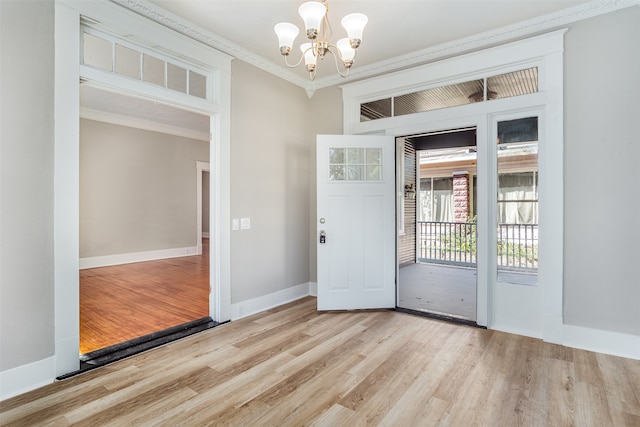 empty room with a notable chandelier, ornamental molding, and light wood-type flooring