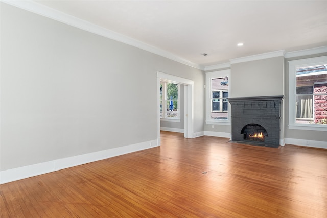 unfurnished living room featuring wood-type flooring, crown molding, and a brick fireplace