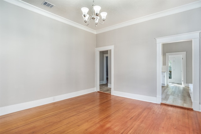 spare room featuring crown molding, wood-type flooring, and a notable chandelier