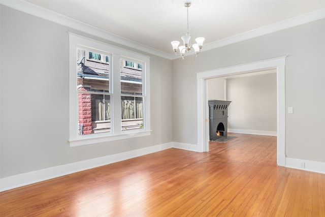 unfurnished room featuring a notable chandelier, hardwood / wood-style flooring, and ornamental molding