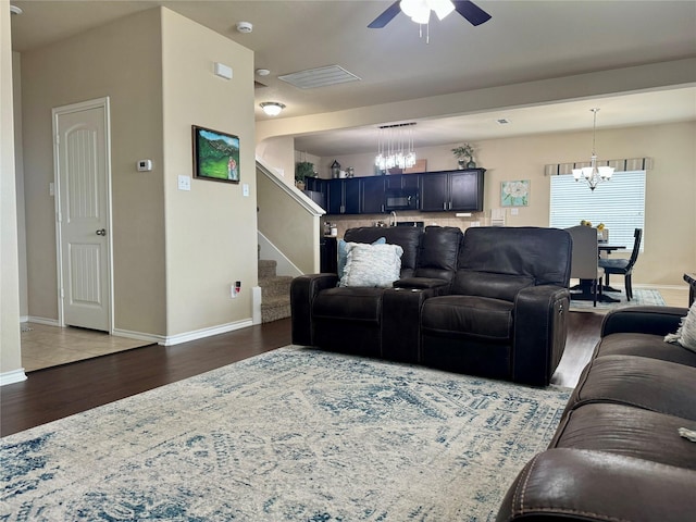 living room featuring dark wood-type flooring and ceiling fan with notable chandelier