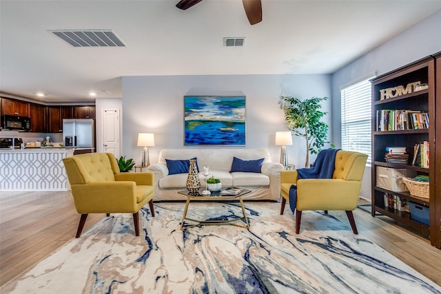 living room with ceiling fan, sink, and light hardwood / wood-style floors