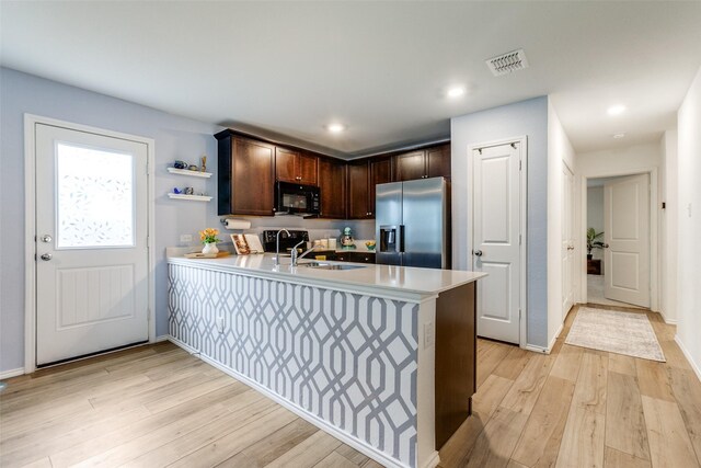 kitchen featuring kitchen peninsula, sink, light hardwood / wood-style floors, dark brown cabinetry, and stainless steel refrigerator with ice dispenser