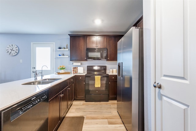 kitchen featuring dark brown cabinetry, sink, black appliances, and light hardwood / wood-style floors