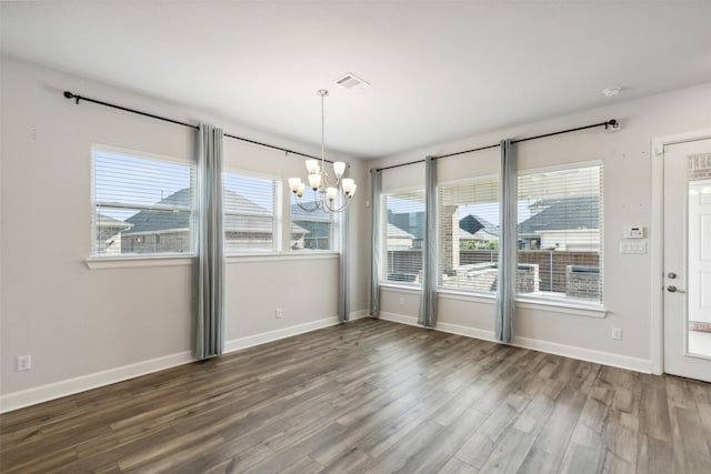 unfurnished dining area with an inviting chandelier and dark hardwood / wood-style flooring