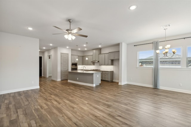 kitchen featuring gray cabinets, sink, hanging light fixtures, a center island with sink, and light hardwood / wood-style flooring