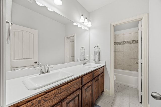 full bathroom with tile patterned floors, tiled shower / bath, vanity, and toilet