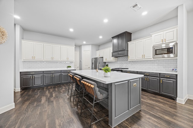 kitchen with an island with sink, white cabinets, and stainless steel appliances