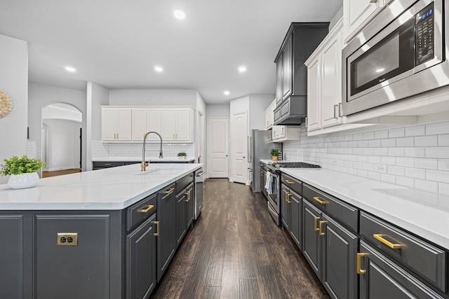 kitchen featuring white cabinets, sink, dark hardwood / wood-style floors, an island with sink, and appliances with stainless steel finishes