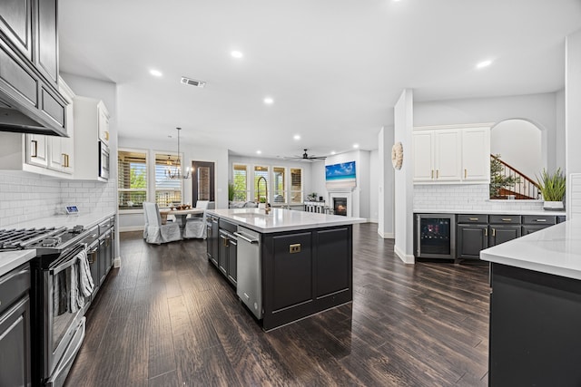 kitchen featuring white cabinetry, wine cooler, dark hardwood / wood-style flooring, an island with sink, and appliances with stainless steel finishes