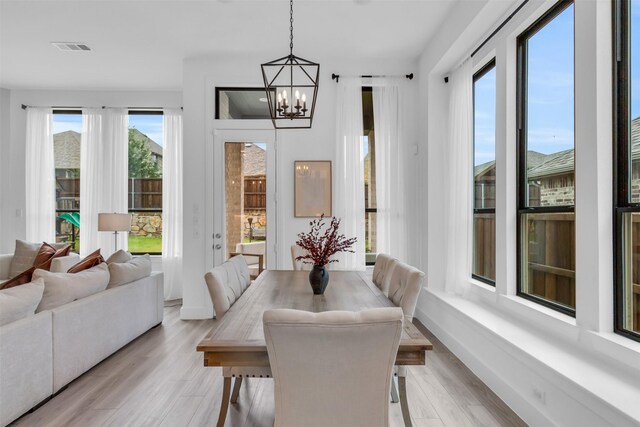 dining area with light wood-type flooring and a notable chandelier