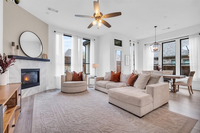 living room with ceiling fan, light wood-type flooring, and a high end fireplace