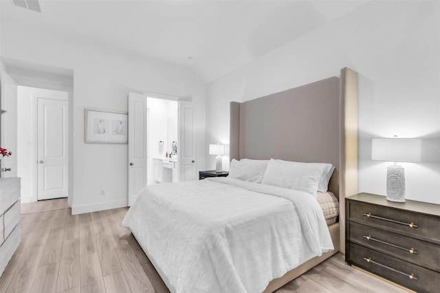 bedroom featuring light wood-type flooring, connected bathroom, and vaulted ceiling