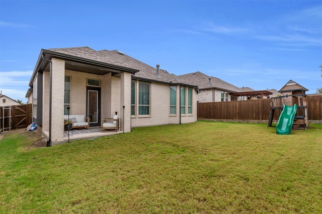 rear view of property with a playground, a yard, and a patio