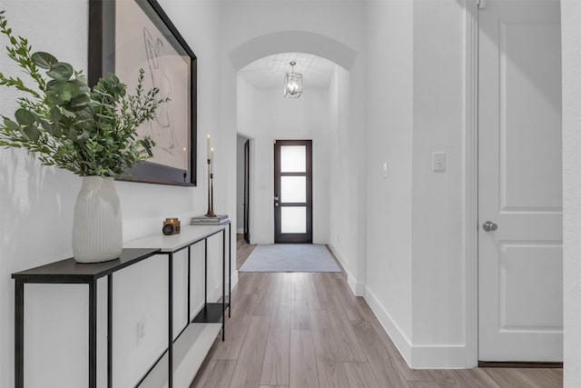 entryway with light wood-style floors, baseboards, and arched walkways