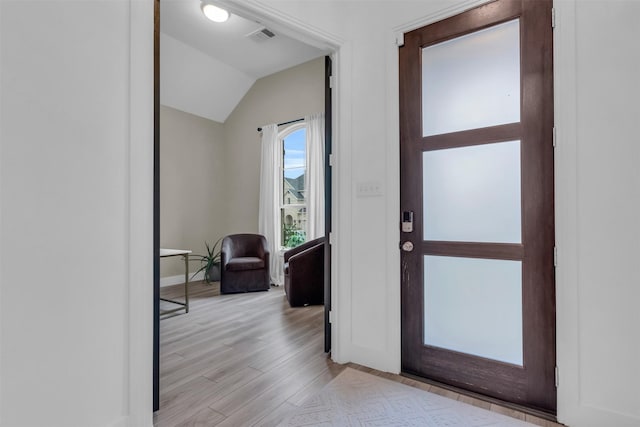 foyer entrance featuring lofted ceiling, light wood-style flooring, visible vents, and baseboards