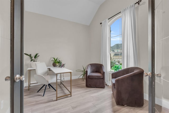 sitting room with light wood finished floors, baseboards, and vaulted ceiling