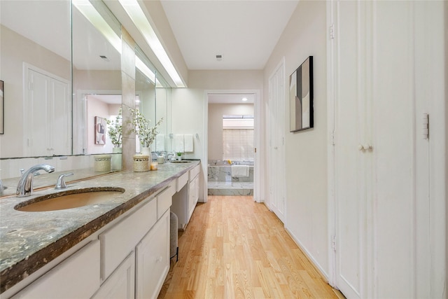 bathroom featuring hardwood / wood-style flooring, vanity, and a bath