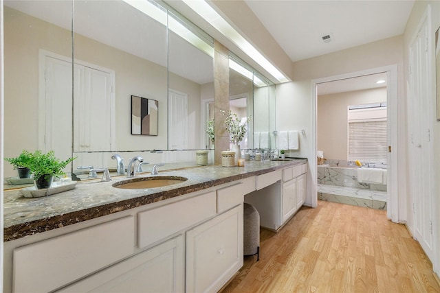 bathroom featuring tiled tub, vanity, and hardwood / wood-style flooring