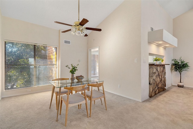 dining room with plenty of natural light, light colored carpet, and high vaulted ceiling