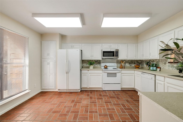 kitchen with tasteful backsplash, white cabinetry, sink, and white appliances