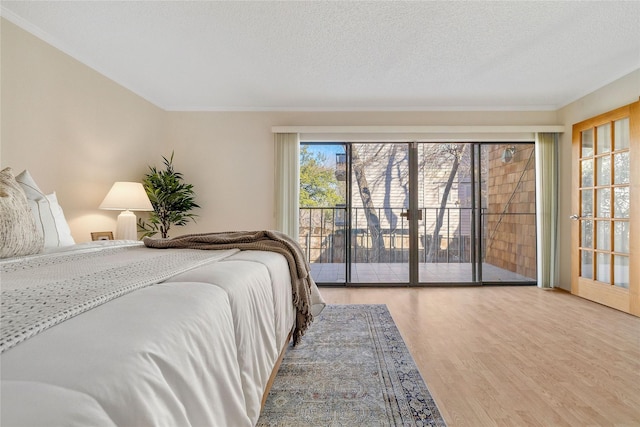 bedroom with hardwood / wood-style floors, access to outside, and a textured ceiling