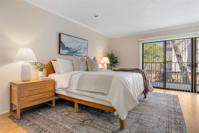 bedroom with hardwood / wood-style floors, access to outside, ornamental molding, and a textured ceiling