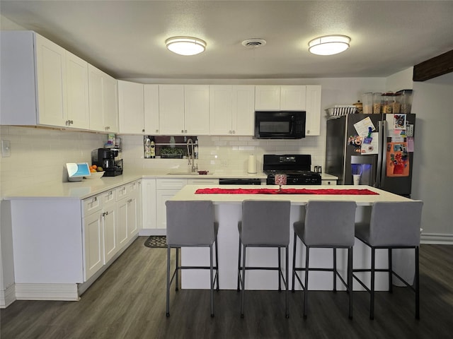 kitchen with a kitchen island, white cabinetry, a breakfast bar area, dark hardwood / wood-style flooring, and black appliances