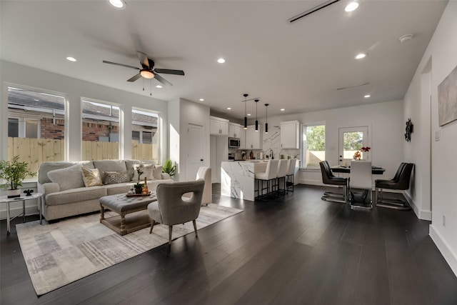 living room with dark wood-type flooring and ceiling fan