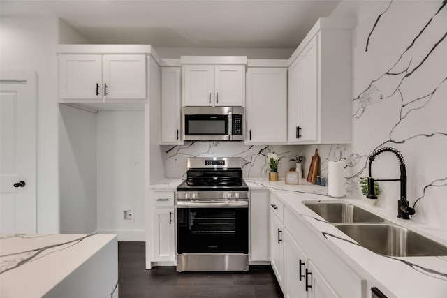 kitchen featuring white cabinetry, sink, decorative backsplash, stainless steel appliances, and light stone countertops