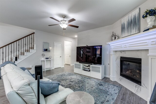 living room with ceiling fan, a high end fireplace, and light hardwood / wood-style flooring