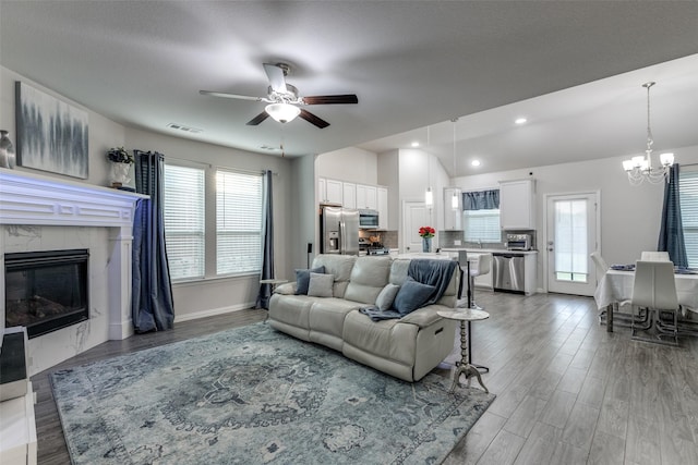 living room with hardwood / wood-style floors, ceiling fan with notable chandelier, and a premium fireplace