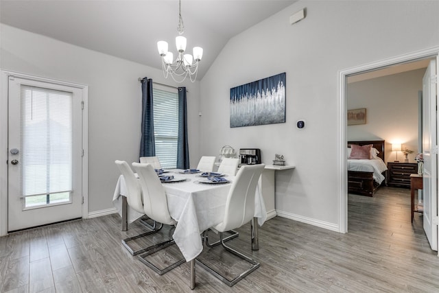 dining area with lofted ceiling, a notable chandelier, and light hardwood / wood-style floors