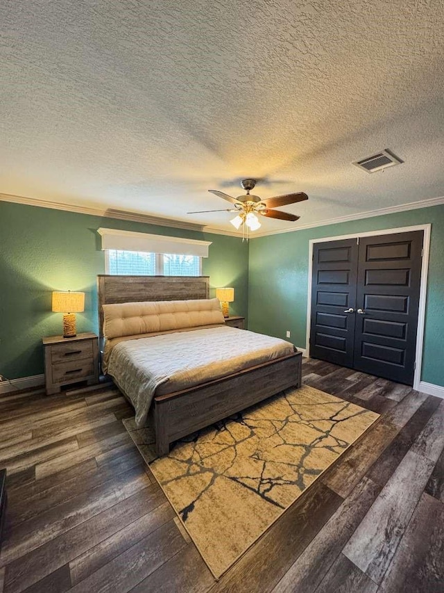 bedroom featuring dark wood-type flooring, ceiling fan, crown molding, and a textured ceiling