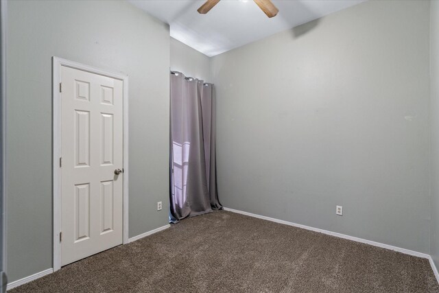 unfurnished bedroom with ceiling fan and dark colored carpet