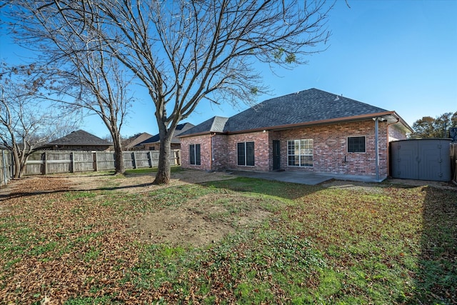 rear view of house with a patio area, a shed, and a yard