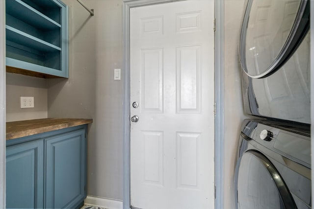 washroom with cabinets and stacked washer / dryer