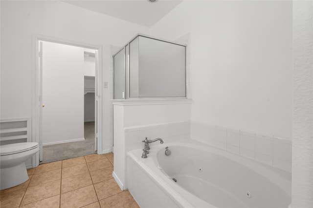 bathroom with tile patterned flooring, a tub to relax in, and toilet