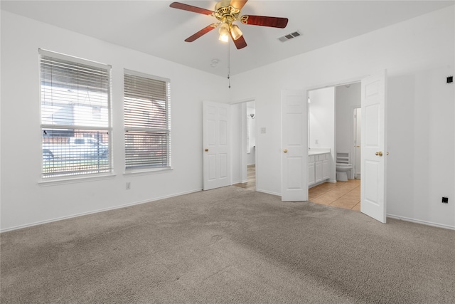 unfurnished bedroom featuring light carpet, ensuite bath, and ceiling fan