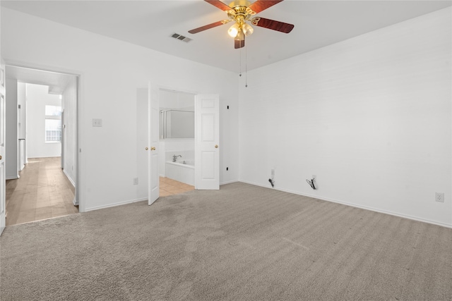 unfurnished bedroom with ensuite bath, ceiling fan, and light carpet